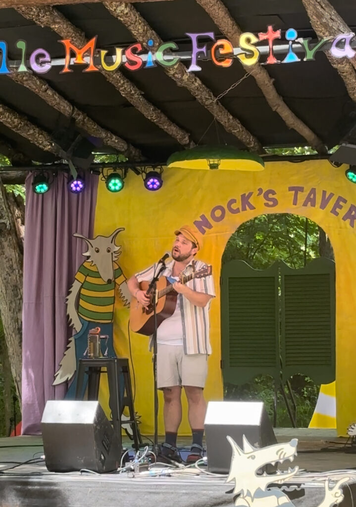 Man playing acoustic guitar and singing on stage.